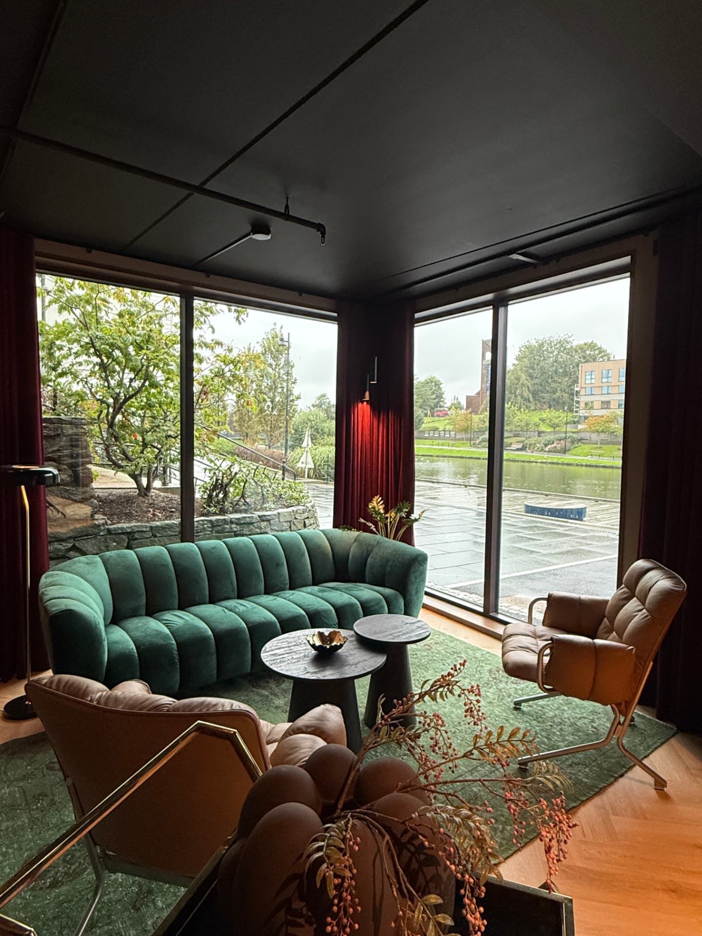 Loungen med grønn velursofa og lenestoler i skinn