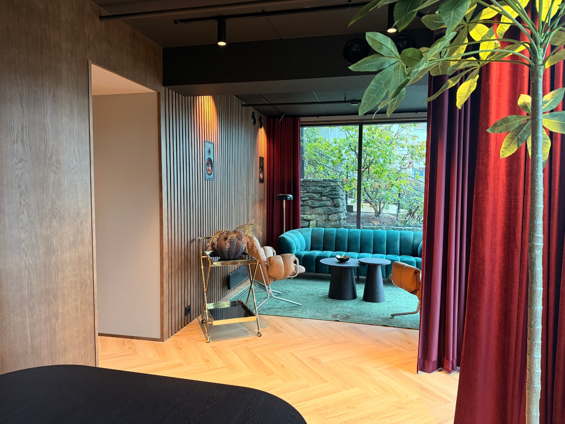 Loungen med burgunder gardiner og grønn velursofa